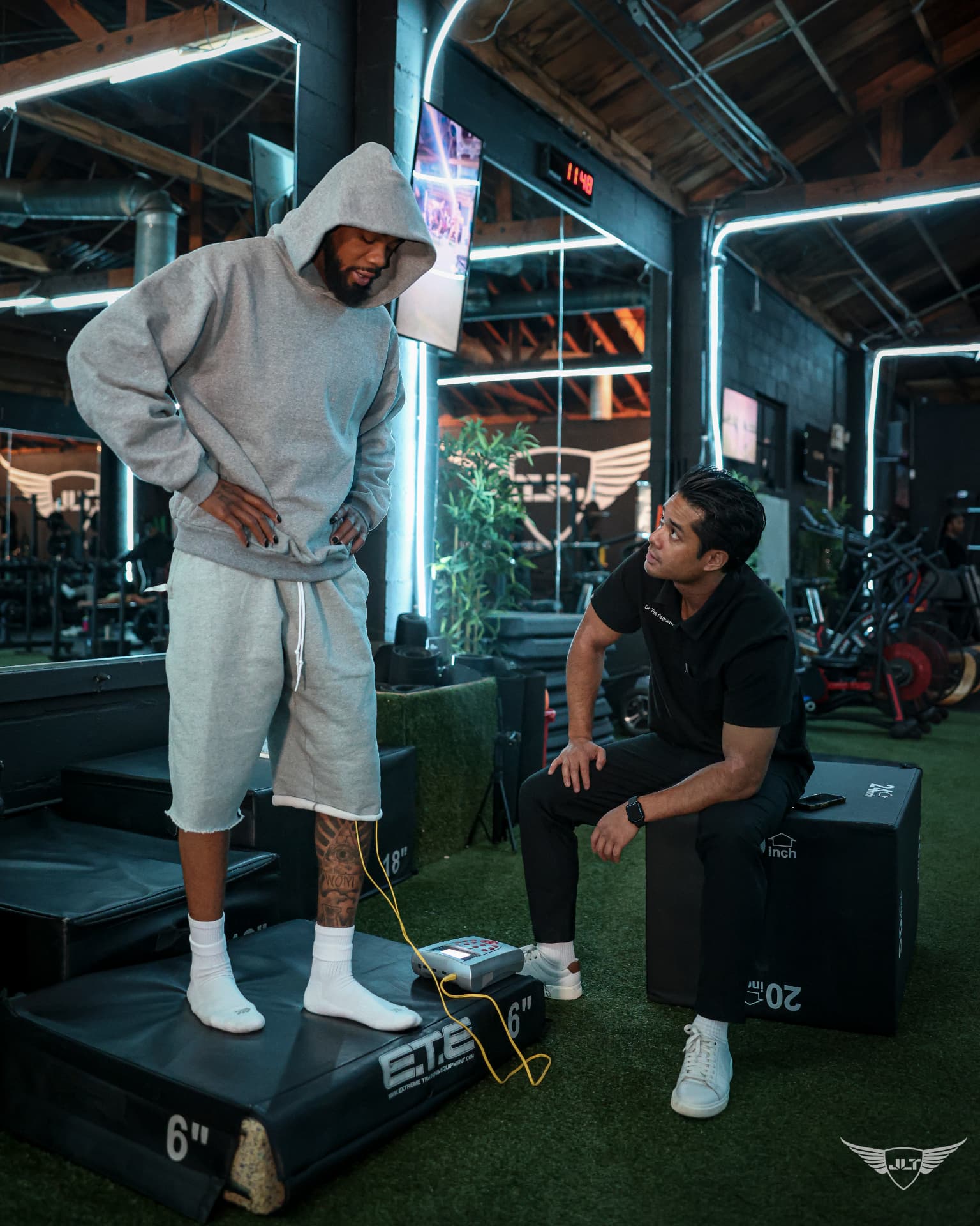 Dr. Tim monitoring an athlete during a stimulation drill on the gym floor